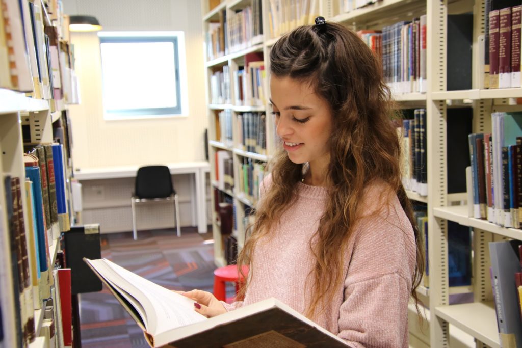 סטודנטית קוראת ספר בספרייה